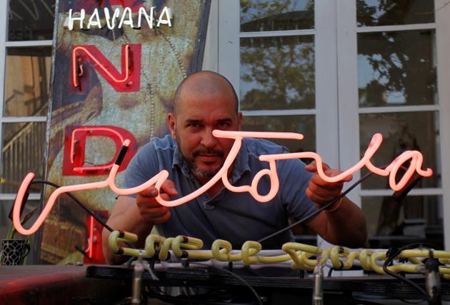 Cuban artist Kadir Lopez Nieves poses with one reading, "Victory", at his workshop and gallery, in Havana.(REUTERS)