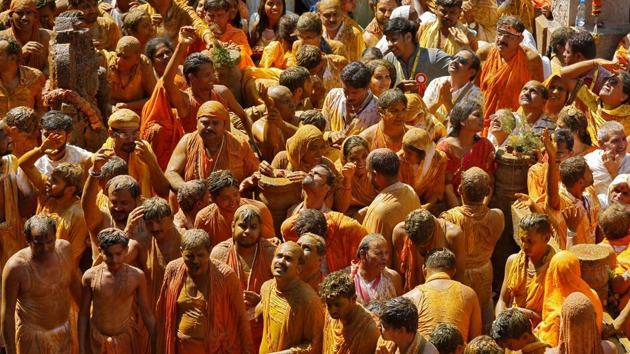 Devotees daubed in turmeric paste stand next to the feet of statue as they celebrate the anointing ceremony. (REUTERS) Devotees daubed in turmeric paste stand next to the feet of statue as they celebrate the anointing ceremony. (REUTERS)