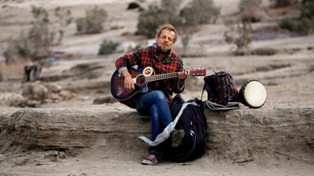 Zina, a tourist from Belarus, plays his guitar as he sits on the shore. “Half the world is hi-tech. I’m with the other half,” said Mark, another hermit living here. Often relying on the kindness of strangers for food, they live on the beach without electricity or a mobile phone. (Ronen Zvulun / REUTERS) Zina, a tourist from Belarus, plays his guitar as he sits on the shore. “Half the world is hi-tech. I’m with the other half,” said Mark, another hermit living here. Often relying on the kindness of strangers for food, they live on the beach without electricity or a mobile phone. (Ronen Zvulun / REUTERS)