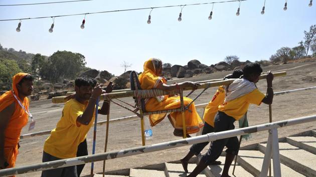 Devotees carry an elderly pilgrim in a palanquin as they make their way towards the shrine. Located between the two hillocks of Vindyagiri and Chandragiri, Shravanabelagola has been a Jain pilgrimage centre for the past 2,500 years and stands testimony to ‘Tyaga’ (renunciation) and the message of ‘Ahimsa’ (non-violence), which embody the Jain way of life. (Aijaz Rahi / AP) Devotees carry an elderly pilgrim in a palanquin as they make their way towards the shrine. Located between the two hillocks of Vindyagiri and Chandragiri, Shravanabelagola has been a Jain pilgrimage centre for the past 2,500 years and stands testimony to ‘Tyaga’ (renunciation) and the message of ‘Ahimsa’ (non-violence), which embody the Jain way of life. (Aijaz Rahi / AP)
