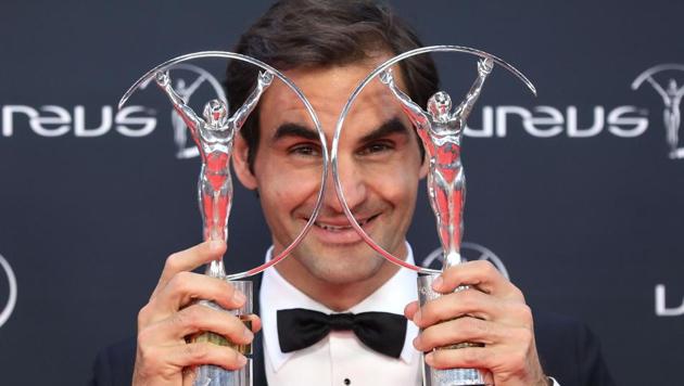 Roger Federer poses with his sportsman and comeback award trophies during the 2018 Laureus World Sports Awards.(AFP)