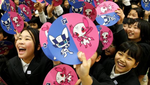 School students hold paper fans featuring the mascots for the Tokyo 2020 Olympics and Paralympics. (REUTERS)