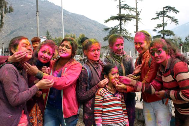 People smear colours on each other’s face and indulge in a feast celebrating a plentiful harvest during the Holi festival at Dhalpur ground in Kullu.   (Aqil Khan/HT) 