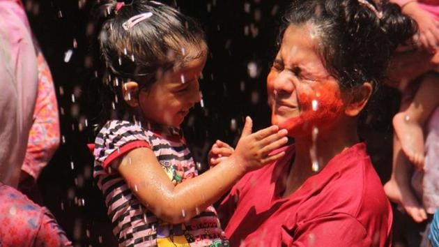 A small child plays with colour in the safety of her mother’s arms.