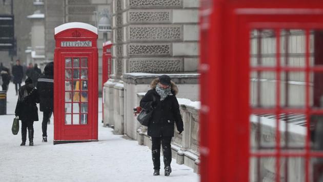 A woman walks down Whitehall as snow falls in London. Most schools across Britain and Ireland are closed, as were many businesses. (Daniel Leal Olivas / AFP)