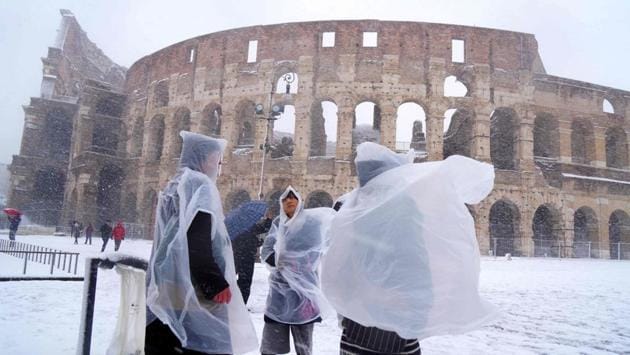 Japanese tourists put on plastic coats as they visit the ancient Colosseum during a the first snowfall in six years in Rome. (Vincenzo Pinto / AFP) 
