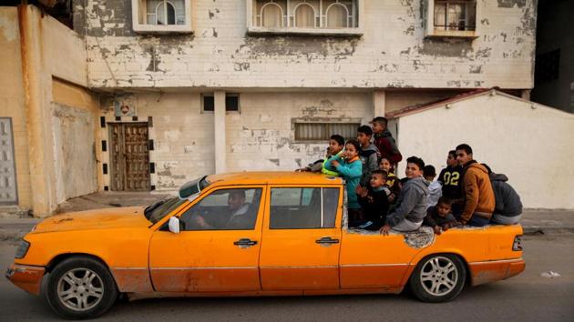 Palestinian children sit on the back of a Mercedes 6-door taxi converted into a pick-up vehicle in the al-Shatee refugee camp in Gaza City. (Mahmud Hams / AFP) 