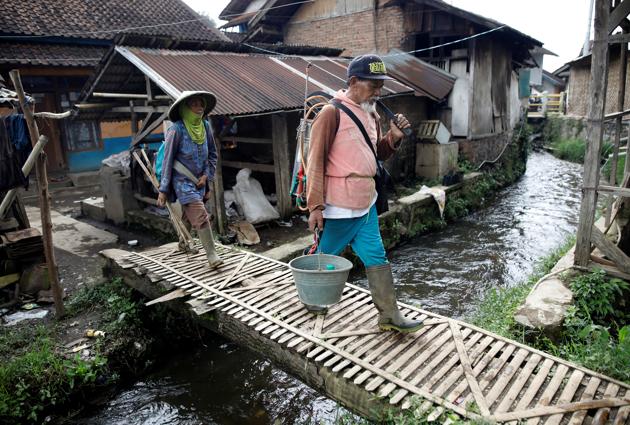 Farmers walk over a stream near Cisanti Lake, the source of the Citarum river, in the mountains south of Bandung, Indonesia. As it burbles past terraced rice paddies and quiet farming villages in the highlands towards the sea its charm swiftly evaporates as the Citarum, often labelled the world’s most polluted, descends past crowded factories and homes that dump a pungent stew of garbage, waste and sewage into its 300-km stretch. (Darren Whiteside / REUTERS)