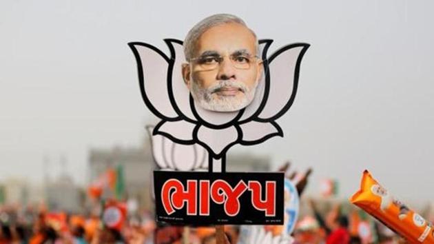 A supporter holds up a cut-out of a lotus, the election symbol of BJP, with an image of Prime Minister Narendra Modi during a campaign meeting ahead of Gujarat state assembly election, in Kalol. (Reuters File Photo) A supporter holds up a cut-out of a lotus, the election symbol of BJP, with an image of Prime Minister Narendra Modi during a campaign meeting ahead of Gujarat state assembly election, in Kalol. (Reuters File Photo)