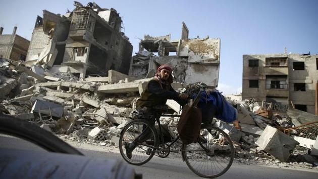 A handicapped man rides a bicycle past damaged buildings in the besieged town of Douma in eastern Ghouta in Damascus, Syria, March 1. (REUTERS) A handicapped man rides a bicycle past damaged buildings in the besieged town of Douma in eastern Ghouta in Damascus, Syria, March 1. (REUTERS)