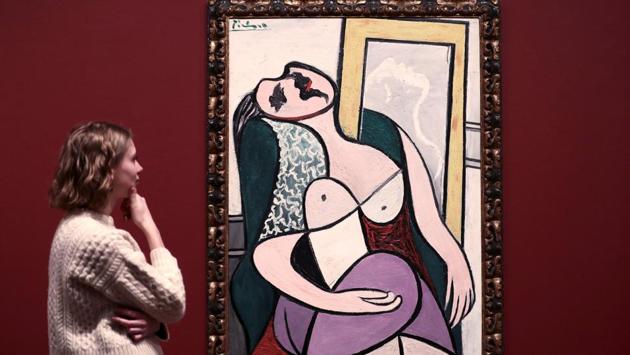 An employee poses with Picasso's 'Sleeping Woman by a Mirror' painting at the Picasso 1932 - Love, Fame, Tragedy exhibition at the Tate Modern in London. (REUTERS) An employee poses with Picasso's 'Sleeping Woman by a Mirror' painting at the Picasso 1932 - Love, Fame, Tragedy exhibition at the Tate Modern in London. (REUTERS)