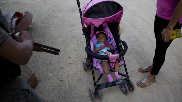 A baby peers up from her stroller at an armed “community police” officer in Xaltianguis. A majority of Mexicans believe self-defence is the best way to protect their community and see nothing wrong in vigilante justice, but going out in war against cartels with sophisticated armaments often results in bloody affairs with both civilians and community police left tallying casualties. (Rebecca Blackwell / AP)