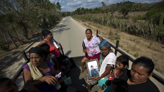 Family members of the six civilians who were killed in La Concepcion group ride home carrying photographs of their loved ones, from meeting with reporters at the town council building where they say their relatives were killed. Some residents say the “community police” groups attack elected officials who don’t agree with them. (Rebecca Blackwell / AP)