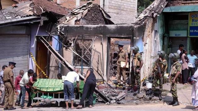 Sri Lanka's Special Task Force and police officers stand guard near a burnt house after a clash between two communities in Digana, central district of Kandy, on Tuesday.(Reuters)