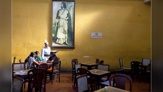 A waiter serves schoolgirls beneath a portrait of Rabindranath Tagore in the Indian Coffee House, Kolkata, 2013.(Stuart Freedman/Tasveer)