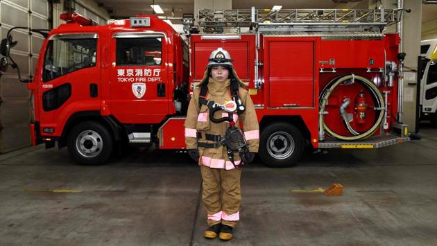 Ran Namise, 24, a firefighter belonging to the command squad, poses for photographs  in front of a fire engine at Kojimachi Fire Station in Tokyo. (Kazuhiro Nogi / AFP) 