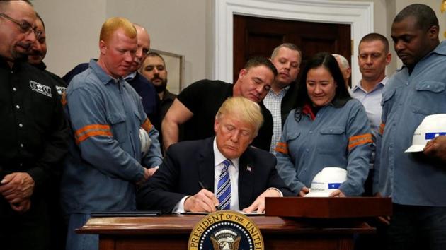 US President Donald Trump signs a presidential proclamation placing tariffs on steel and aluminum imports while surrounded by workers from the steel and aluminum industries at the White House in Washington. (REUTERS) US President Donald Trump signs a presidential proclamation placing tariffs on steel and aluminum imports while surrounded by workers from the steel and aluminum industries at the White House in Washington. (REUTERS)