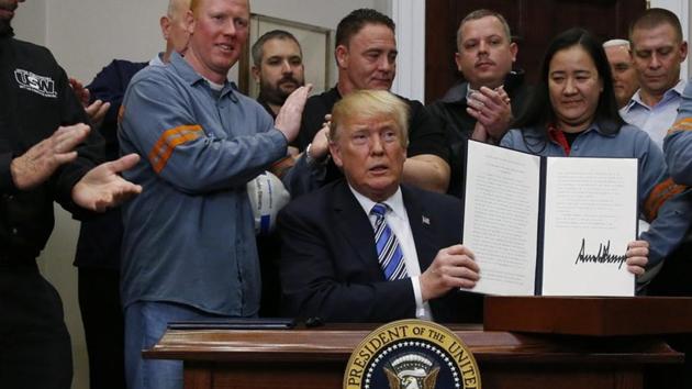 US President Donald Trump holds up a proclamation during a White House ceremony to establish tariffs on imports of steel and aluminium at the White House in Washington, on Thursday.(Reuters photo)