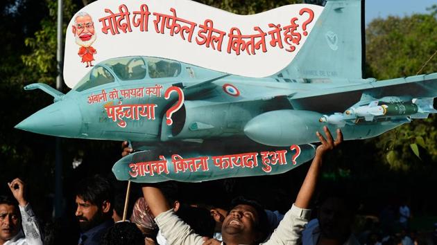 A Congress supporter holds a model of Rafale fighter jet as he shouts slogans during a protest against the Rafale jets deal in New Delhi on March 5.(AFP Photo)