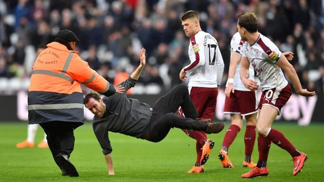 Burnley's English striker Ashley Barnes trips up a pitch invader during the English Premier League football match against West Ham Unitedat the London Stadium.(AFP)