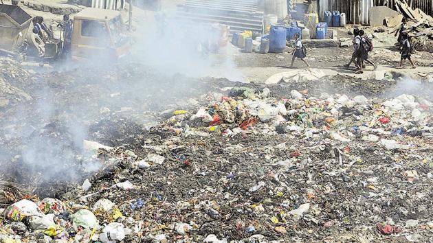 School children walk past an illegal garbage dump yard at Wagholi.(Shankar Narayan/HT PHOTO)