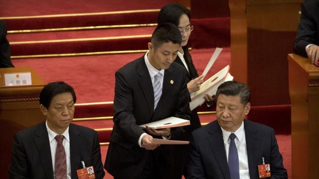 An official hands a ballot to Chinese President Xi Jinping, right, during a plenary session of China's National People's Congress (NPC) at the Great Hall of the People in Beijing, March 11, 2018. China's parliament passed a historic constitutional amendment abolishing presidential term limits that will enable Xi to rule indefinitely. At left is Politburo Standing Committee member Li Zhanshu.(AP Photo)