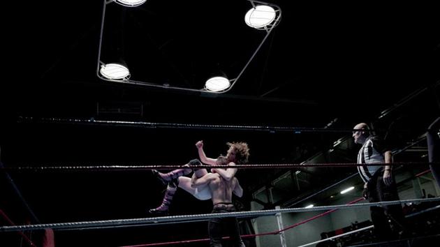 Lord Steven Crowley, top, jumps on Zack during a bout. Its poster featured a masked wrestler gripping French President Emmanuel Macron — decried by critics as a “president of the rich” for his pro-business policies — in a stranglehold. Saxophonists begun the event marching in wearing headgear and capes, just like wrestling heroes. (Kamil Zihnioglu / AP) Lord Steven Crowley, top, jumps on Zack during a bout. Its poster featured a masked wrestler gripping French President Emmanuel Macron — decried by critics as a “president of the rich” for his pro-business policies — in a stranglehold. Saxophonists begun the event marching in wearing headgear and capes, just like wrestling heroes. (Kamil Zihnioglu / AP)
