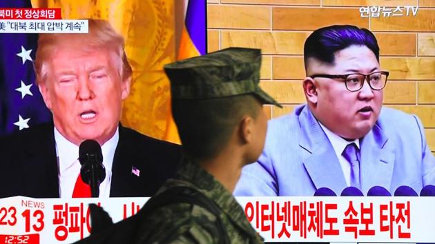 A South Korean soldier walks past a television screen showing pictures of US President Donald Trump (left) and North Korean leader Kim Jong Un at a railway station in Seoul on March 9, 2018. (AFP)