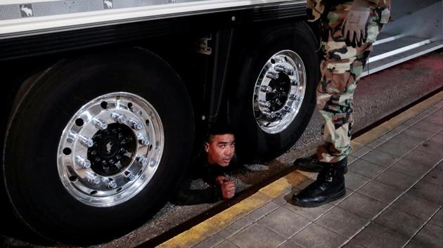 “Get down! Get down from there!” an officer with the coast guard’s special forces yelled at the man peering at him from under a truck lined up for embarkation control, who was then handcuffed and escorted away at the port of Patras in Greece. (Alkis Konstantinidis / REUTERS) “Get down! Get down from there!” an officer with the coast guard’s special forces yelled at the man peering at him from under a truck lined up for embarkation control, who was then handcuffed and escorted away at the port of Patras in Greece. (Alkis Konstantinidis / REUTERS)