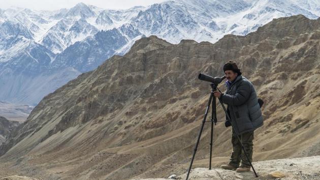 Sonam, a senior spotter scans the mountains for the snow leopard with his spotting scope.  (Pratik Chorge / HT Photo) 