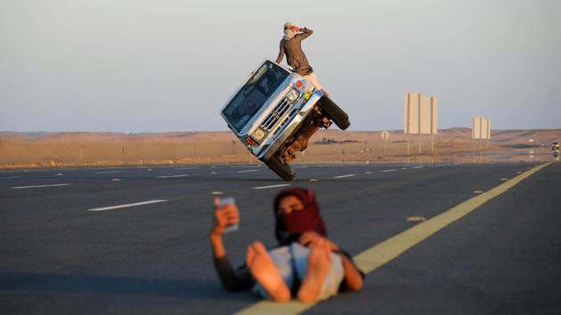 Saudi men perform a stunt known as “sidewall skiing” (driving on two wheels) as a youth takes a selfie in Tabuk, Saudi Arabia. (Mohamed Al Hwaity / REUTERS) Saudi men perform a stunt known as “sidewall skiing” (driving on two wheels) as a youth takes a selfie in Tabuk, Saudi Arabia. (Mohamed Al Hwaity / REUTERS)