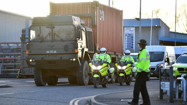 Police officers escort an army truck, carrying a freight container laden with the car of Sergei Skripal, as it is driven from the Churchfields industrial estate in Salisbury, southern England on Friday as part of investigations in connection with the poisoning of the former Russian spy.(AFP)