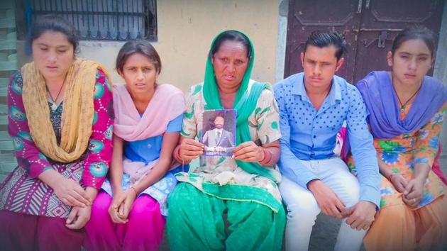 Family members of Balbir Chand, who has been missing in Iraq since 2014 and was not on the official list of 39 Indians declared dead, hold his photo at their residence in Selkiana village on Tuesday.(HT Photo)