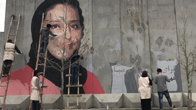 This handout from the Afghan social activist group ArtLords taken on March 8, 2018 shows artists painting a mural of Hamida Barmaki, who, along with her husband and children, was killed in a 2011 suicide attack on a supermarket, on a blast wall near the home of warlord Gulbuddin Hekmatyar, whose followers had carried out the attack, in Kabul.(AFP) This handout from the Afghan social activist group ArtLords taken on March 8, 2018 shows artists painting a mural of Hamida Barmaki, who, along with her husband and children, was killed in a 2011 suicide attack on a supermarket, on a blast wall near the home of warlord Gulbuddin Hekmatyar, whose followers had carried out the attack, in Kabul.(AFP)
