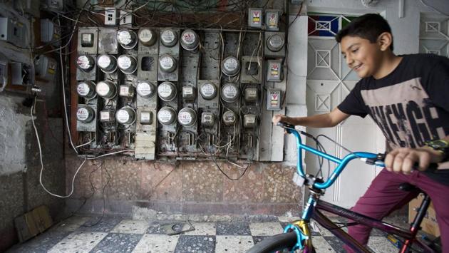 A boy living with his family in a tent camp on the street fetches his bike from inside a their damaged building at Independencia 18. Despite sunken floors and caved-in walls, residents need to enter daily to use the bathroom, shower, and retrieve stored belongings. (Rebecca Blackwell / AP)