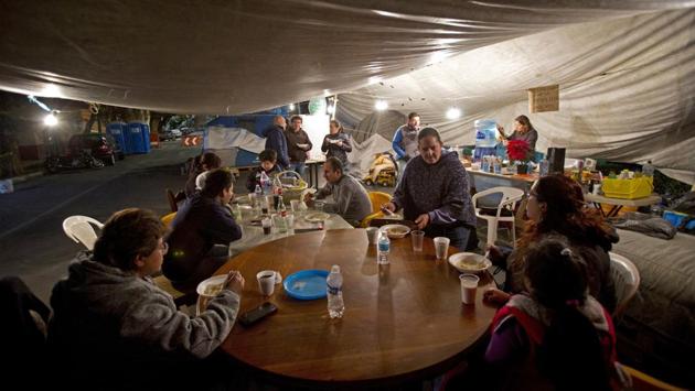 Residents of a damaged building gather for a hot dinner brought by volunteers in the tent camp where they have been living outside their building in Mexico City. At first there was a lot of solidarity. Some let neighbours use their bathrooms and shared food. But as days turned to weeks and then months, sentiments shifted. (Rebecca Blackwell / AP)