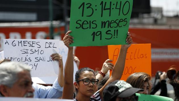 A resident holds up a sign that read “13:14:40, six months 19S,” referring to the time and day of the earthquake. People who lost homes and businesses have been protesting the slow rate of progress with demolitions and repairs. Only a handful of the highest risk buildings have so far been torn down, with others yet to receive any answer at all over their fates. (Rebecca Blackwell / AP)