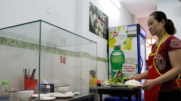 A waitress carries dishes to customers next to the glass-encased table where former US President Barack Obama sat at for a meal. (AFP) A waitress carries dishes to customers next to the glass-encased table where former US President Barack Obama sat at for a meal. (AFP)