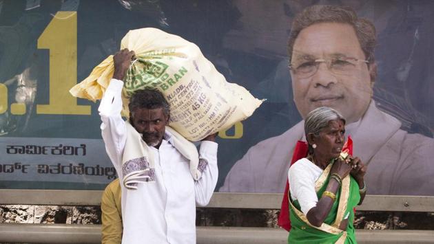 Pedestrians walk past an election campaign billboard featuring an image of Karnataka Chief Minister K. Siddharamaiah, of the Indian National Congress party (INC), displayed at a bus stop in Bengaluru. “People will not be fooled. Centre can write off lakhs of crores of a few industrialists but can’t give debt relief to crores of farmers,” Siddaramaiah said after his tweet against the state BJP. (Prashanth Vishwanathan / Bloomberg) Pedestrians walk past an election campaign billboard featuring an image of Karnataka Chief Minister K. Siddharamaiah, of the Indian National Congress party (INC), displayed at a bus stop in Bengaluru. “People will not be fooled. Centre can write off lakhs of crores of a few industrialists but can’t give debt relief to crores of farmers,” Siddaramaiah said after his tweet against the state BJP. (Prashanth Vishwanathan / Bloomberg)