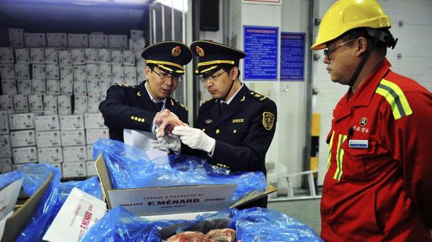 In this April 13, 2017 photo, a warehouse worker watches as government inspectors check imported frozen pork in Qingdao in eastern China's Shandong province. (AP File Photo) In this April 13, 2017 photo, a warehouse worker watches as government inspectors check imported frozen pork in Qingdao in eastern China's Shandong province. (AP File Photo)