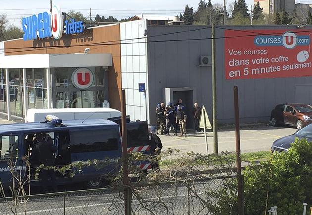 Police gather outside a supermarket in Trebes, southern France, on Friday where an armed man took hostages. (AP) Police gather outside a supermarket in Trebes, southern France, on Friday where an armed man took hostages. (AP)