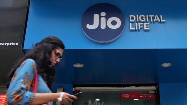 A woman checks her mobile phone as she walks past a mobile store of Reliance Industries’ Jio telecom unit, in Mumbai.(Reuters File)