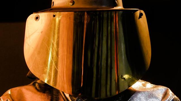 Liquid raw iron is reflected in a protective visor of an employee working at the furnace. In the next step, to reduce the carbon content and strengthen the material, oxygen is blown through the iron. (Markus Schreiber / AP) 