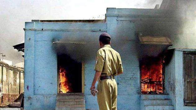 In this photograph taken on February 28, 2002, a policeman looks as fire rages in shops in Ahmedabad following an attack by a mob.(AFP File Photo)