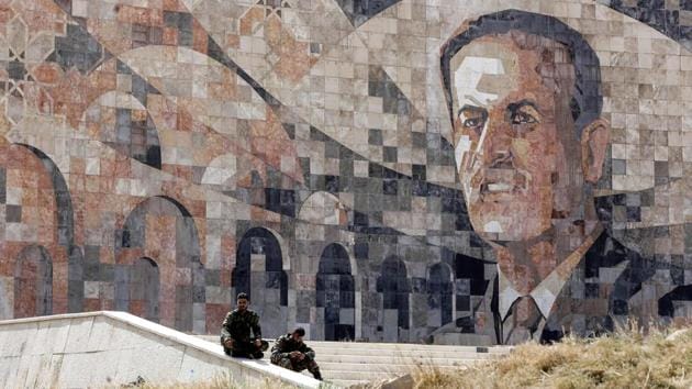 Regime forces sit by a marble mosaic monument depicting a picture of late President Hafez al-Assad. A third set of talks, over Douma are more likely to result in an agreement allowing rebels to maintain their presence and could involve turning Jaish al-Islam to a local force, the return of regime institutions and services like electricity and water to Douma. (Louai Beshara / AFP) Regime forces sit by a marble mosaic monument depicting a picture of late President Hafez al-Assad. A third set of talks, over Douma are more likely to result in an agreement allowing rebels to maintain their presence and could involve turning Jaish al-Islam to a local force, the return of regime institutions and services like electricity and water to Douma. (Louai Beshara / AFP)