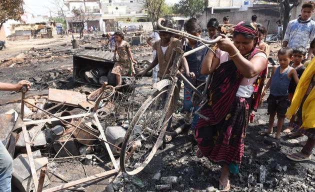 An elderly woman digs out charred cycle out of the ashes from the spot, where a fire broke out in the slum of Parameshwar Enclave Colony of Indira Nagar in Lucknow.(Subhankar Chakraborty/HT Photo)
