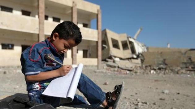 A Yemeni boy school writes as he sits outside a school on March 16, 2017, that was damaged in an air strike in the southern Yemeni city of Taez. (AFP) A Yemeni boy school writes as he sits outside a school on March 16, 2017, that was damaged in an air strike in the southern Yemeni city of Taez. (AFP)