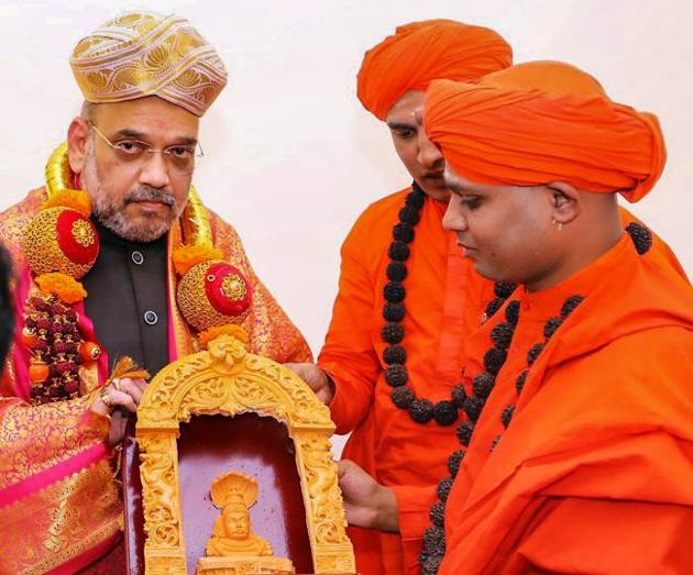 BJP president Amit Shah being presented with a souvenir on his visit to Madara Chennaiah Swamiji mutt, during his state tour ahead of Karnataka elections in Chitradurga on Tuesday.(PTI Photo)