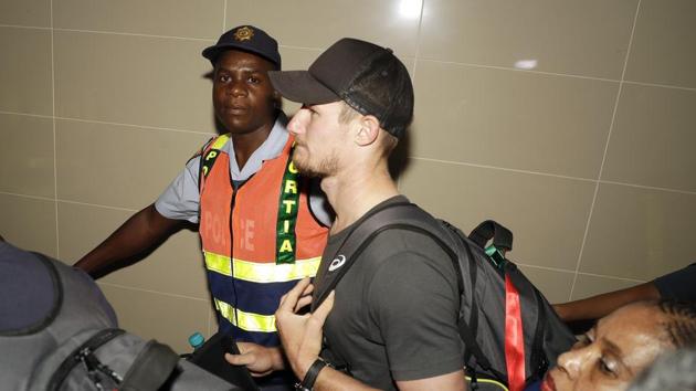 Australia's cricket player Cameron Bancroft is escorted by police officers to the departure area after being sent home from South Africa for ball-tampering in the third Test in Cape Town. (AP)