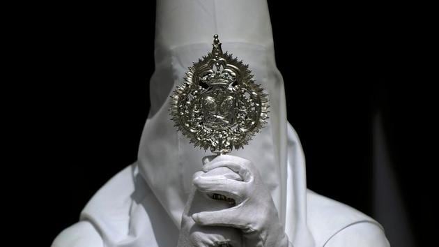 A penitent of the ‘La Paz’ brotherhood takes part in the Palm Sunday procession in Sevilla at the start of the Holy Week on March 25, 2018. Penitents march in hooded robes called capriotes to mask their identity in the public as self-confessed sinners. (Cristina Quicler / AFP) A penitent of the ‘La Paz’ brotherhood takes part in the Palm Sunday procession in Sevilla at the start of the Holy Week on March 25, 2018. Penitents march in hooded robes called capriotes to mask their identity in the public as self-confessed sinners. (Cristina Quicler / AFP)
